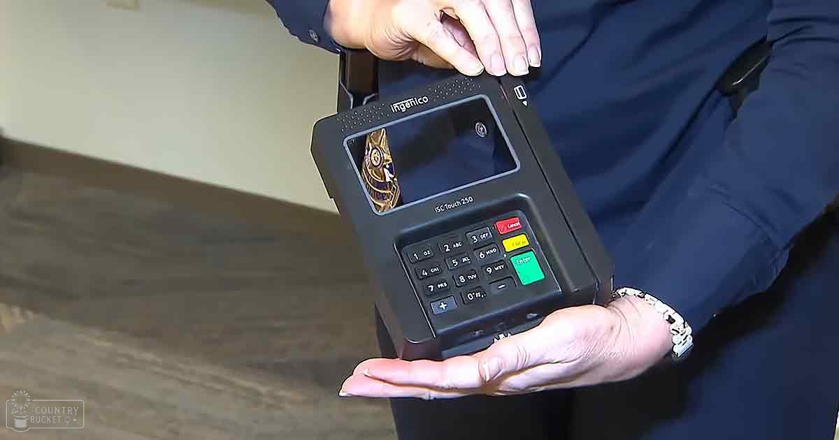 Adult female in work attire holding an ISC Touch 250 portable payment terminal indoors, with focus on the device's keypad and screen.