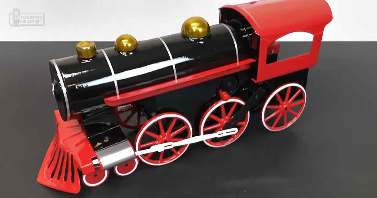 A toy steam locomotive with red wheels, a black body, golden smokestacks, and a red caboose, set against a dark gray surface on a white background