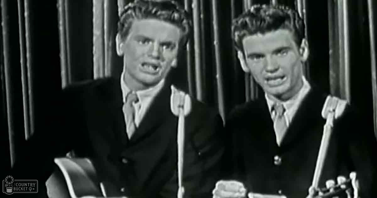 Musical performance scene from mid-20th century with young adult male singers wearing dark suits in a dramatic, ornate setting.