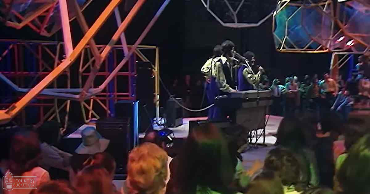 An indoor venue, likely a concert hall or performance space, with musical performers on stage equipped with instruments and audio equipment.