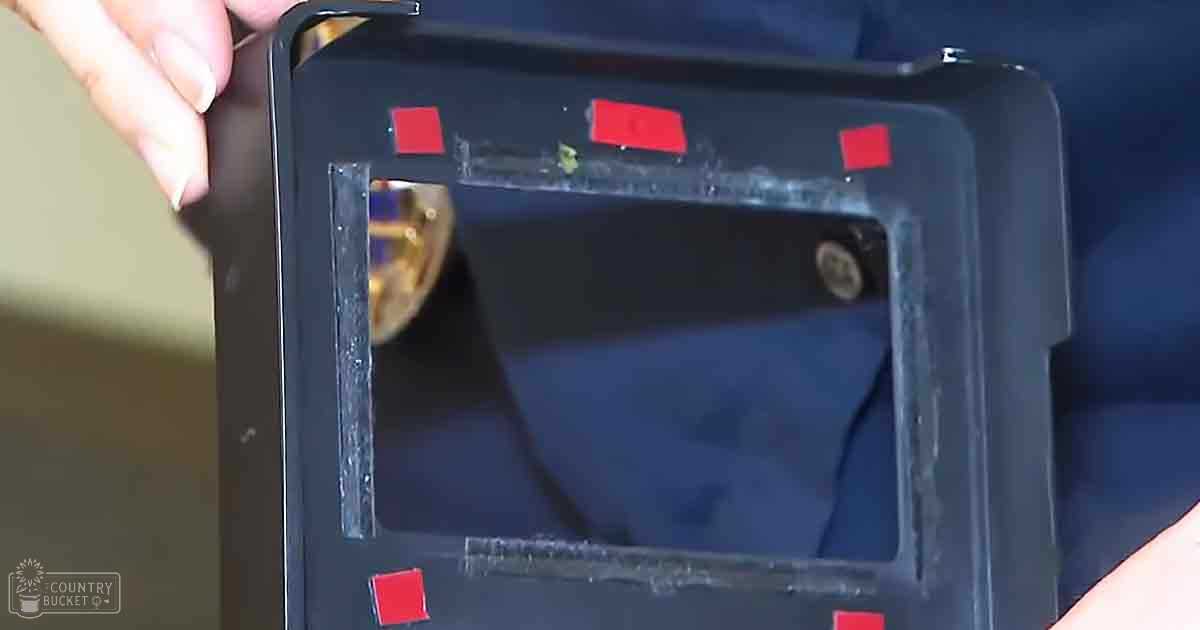 A close-up view of a voting machine with small red stickers, set indoors in bright daylight.