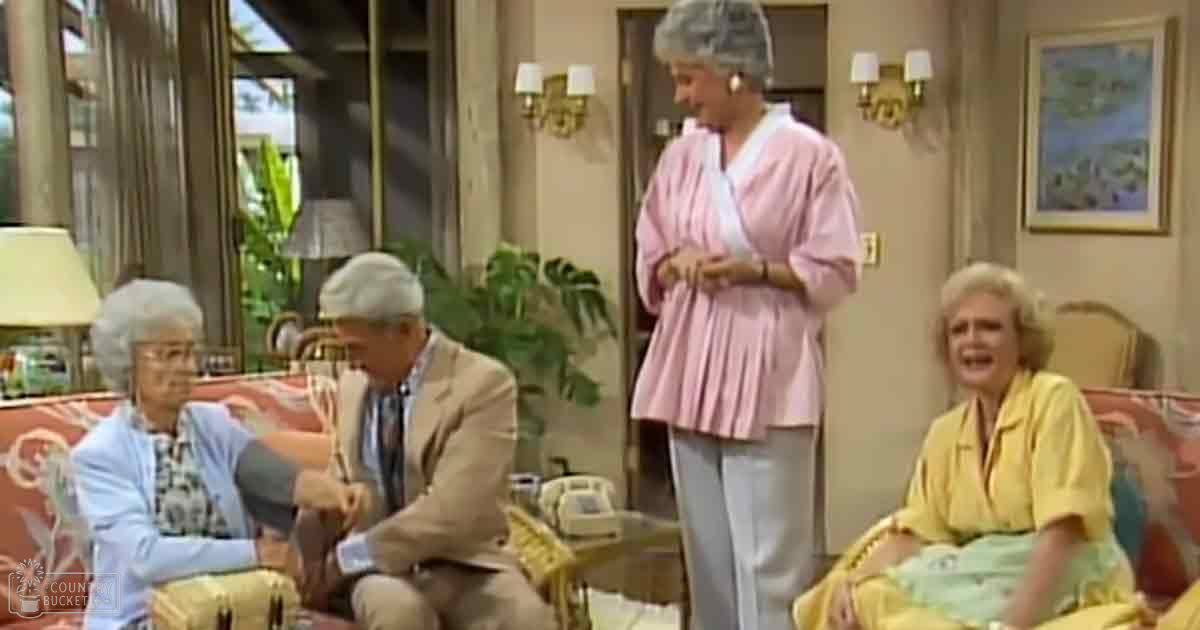 An indoor living room scene with older adults, light clothing, and a red couch.