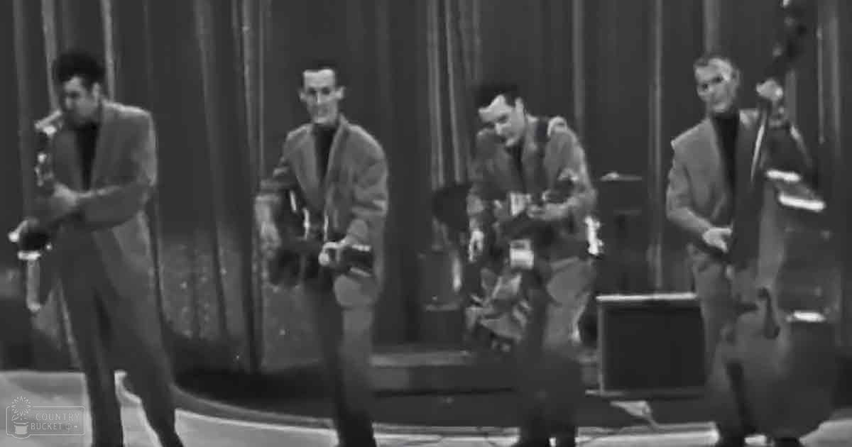 Four individuals dressed in formal mid-20th-century attire playing instruments on a stage with curtains as backdrop.