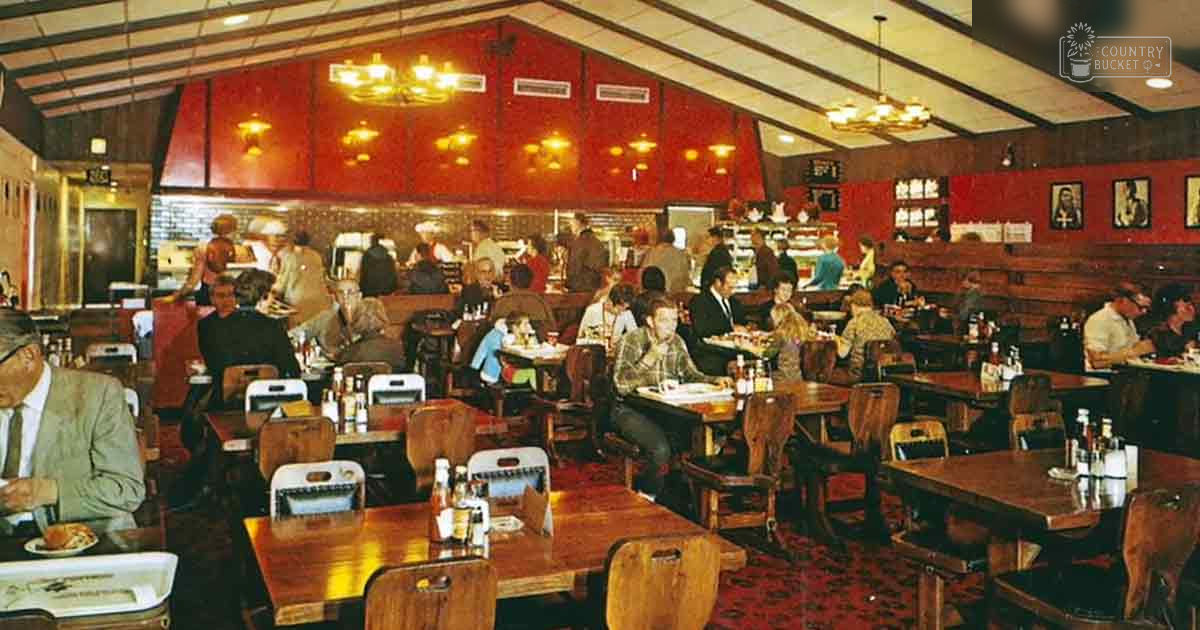 A mid-century restaurant interior with wooden furniture, red walls, and framed pictures on the ceiling; natural light suggests daytime;