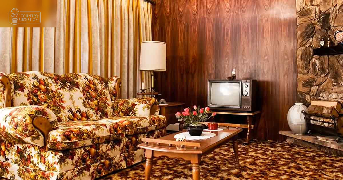 A mid-20th-century living room scene with a floral-patterned sofa and wooden coffee table adorned with pink flowers.