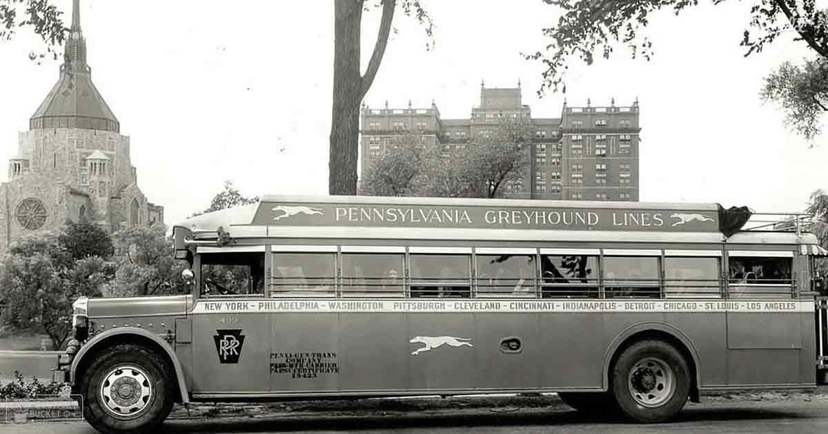 Vintage Pennsylvania Greyhound Lines bus listing cities served, urban environment with church and multi-story building, autumn season, daytime light