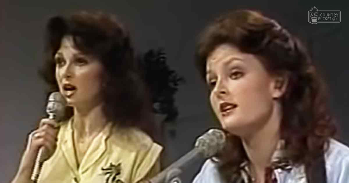 Two women singing in a recording studio setting, wearing light yellow and blue patterned shirts from the 1970s or early 1980s.