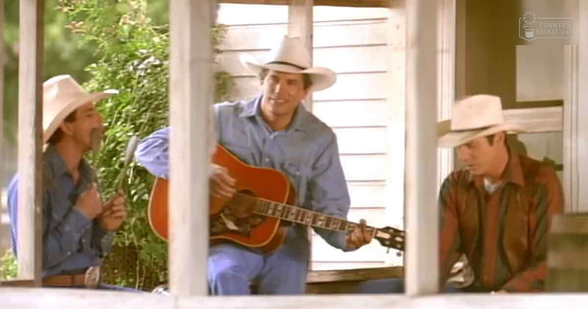 Three adult males playing music outdoors on a porch with shutters, surrounded by greenery; spring or summer day with soft natural light.