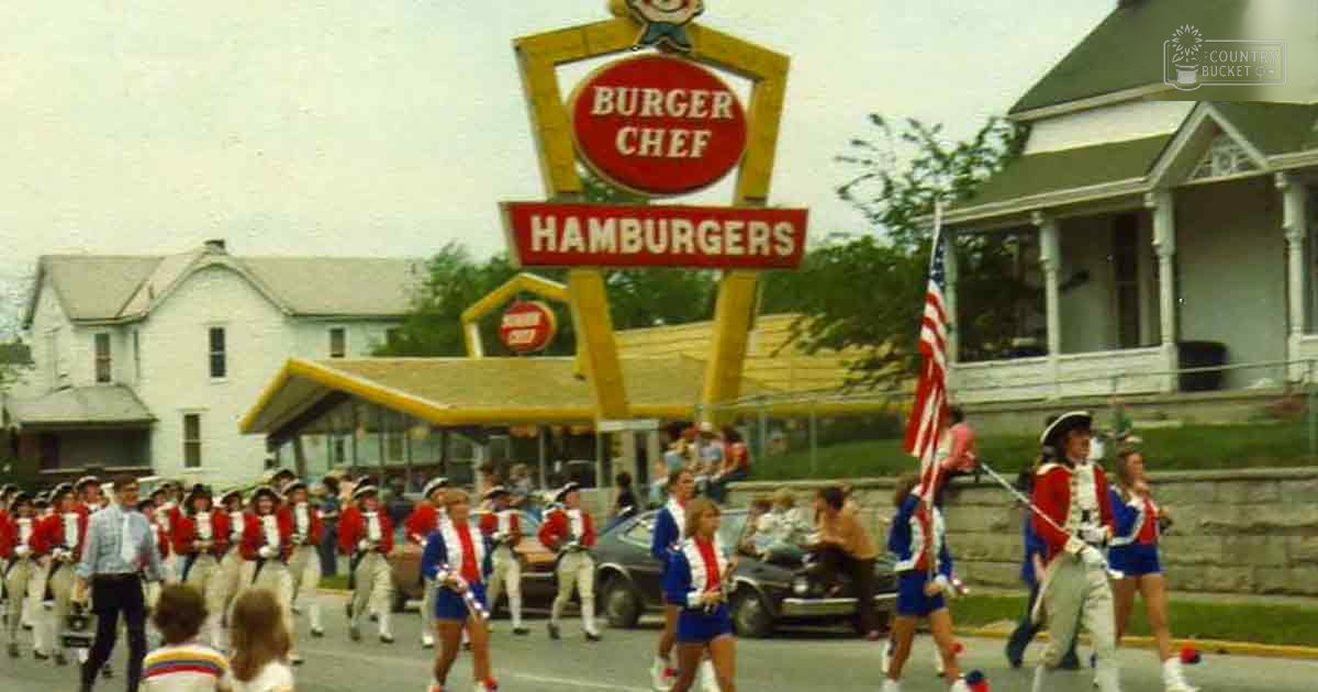 Children in parade attire at a Burger Chef restaurant during spring or summer with overcast skies, suburban neighborhood setting.