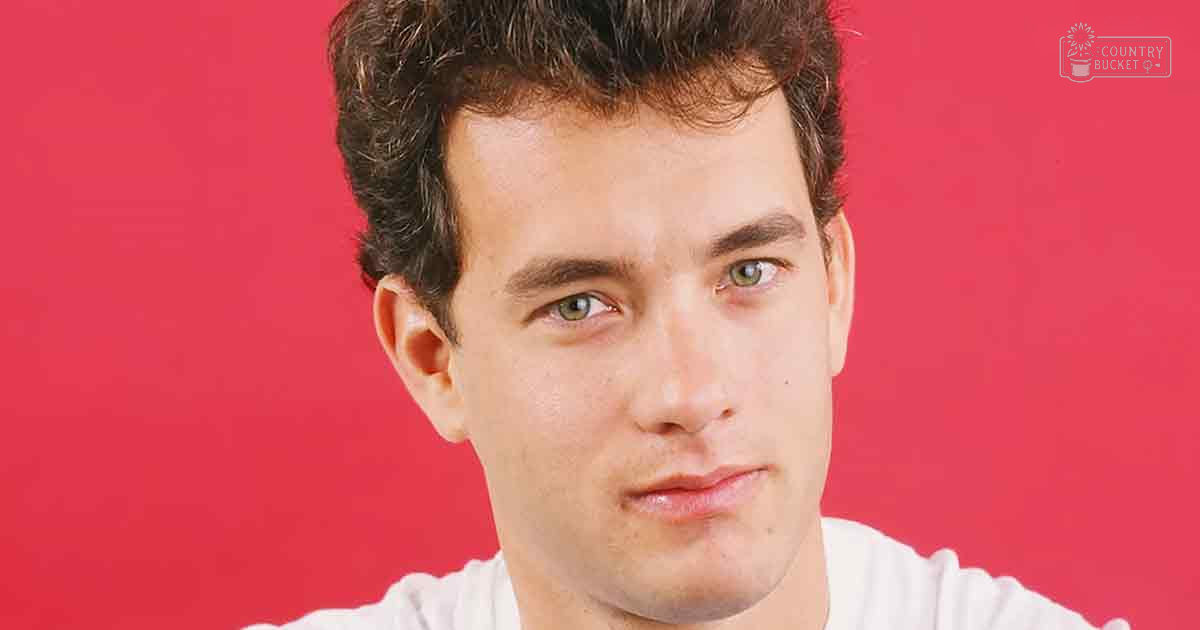 A young adult male in front of a red background wearing a white t-shirt with short sleeves, set against controlled indoor lighting.