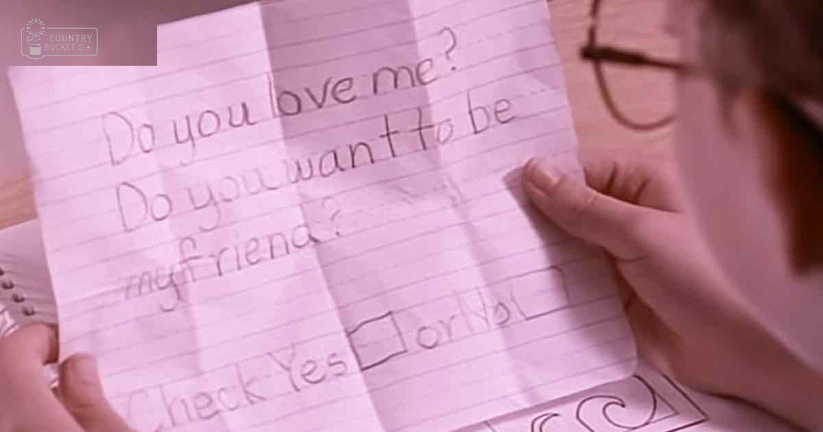 A child holding a handwritten note indoors with soft natural light, pink and white tones.