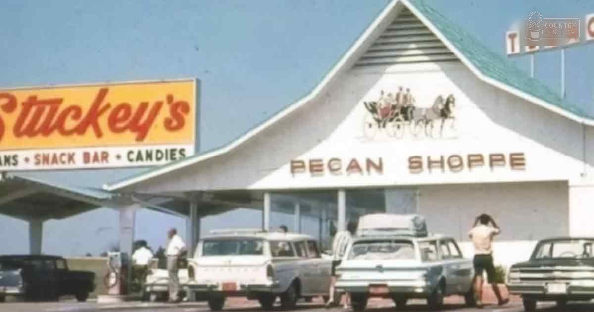 A vintage Stuckey's Pecan Shoppe in Texas with two classic 1950s cars parked nearby, an adult male middle-aged in casual attire and an older adult female in light clothing standing by the shop on a sunny day.
