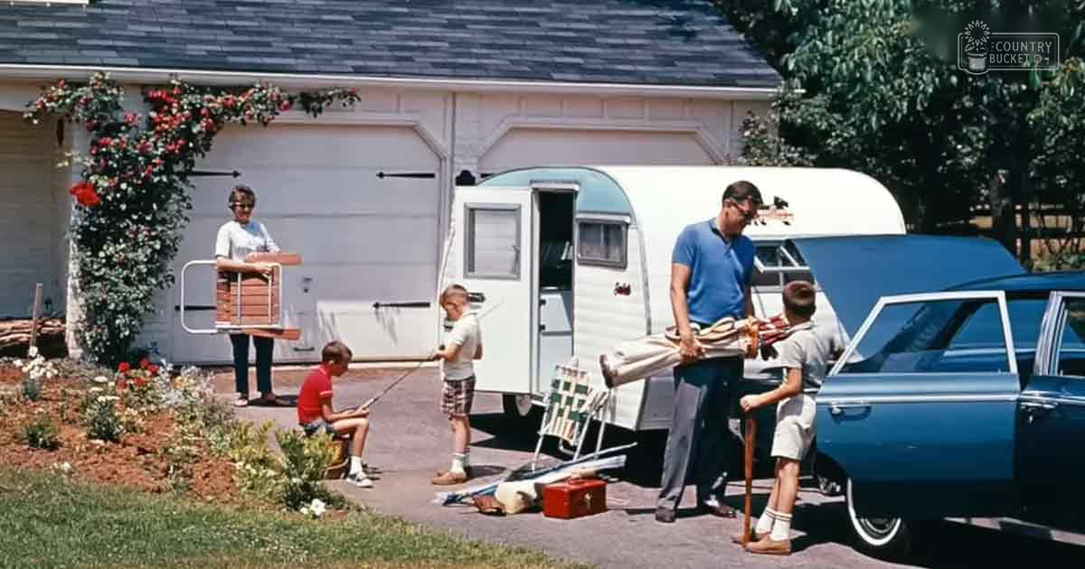 A family prepares to leave their suburban home with a camper trailer and blue car parked in front, set against a backdrop of greenery indicating spring or summer.