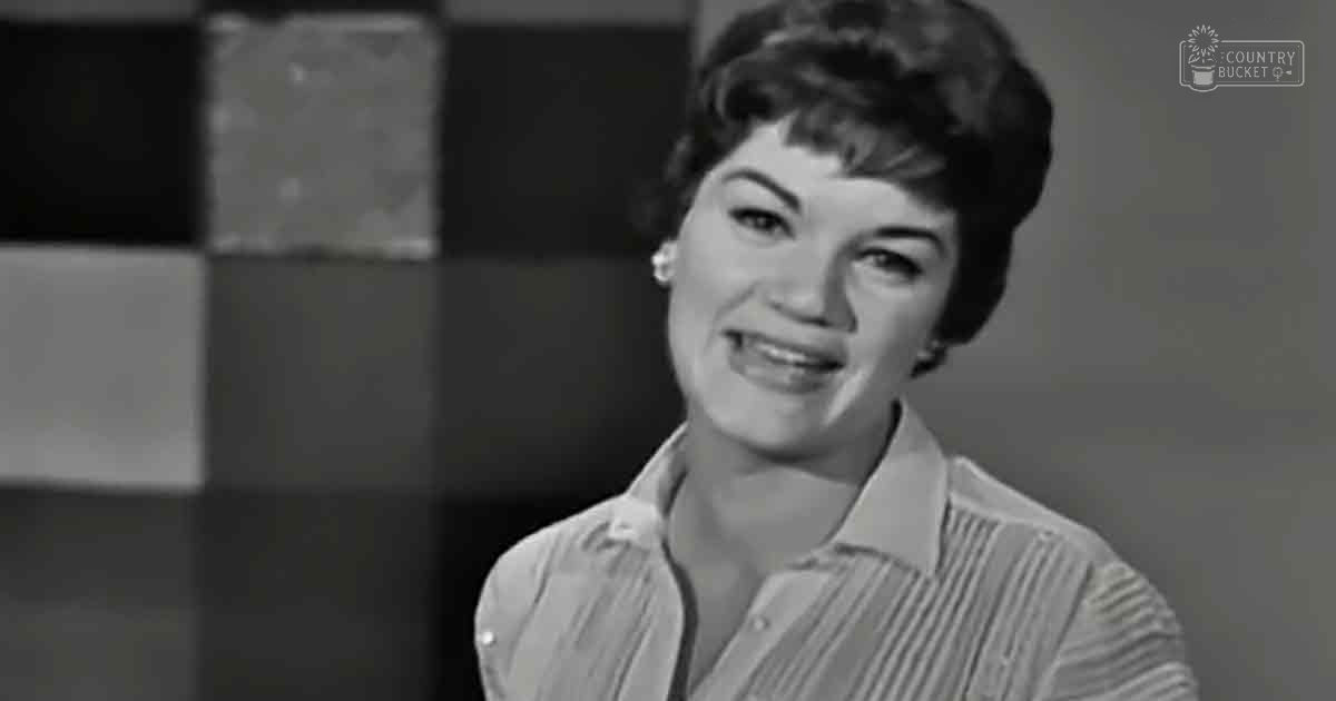 A young adult female wearing a button-down shirt with vertical stripes in an indoor setting, possibly an office or studio environment.