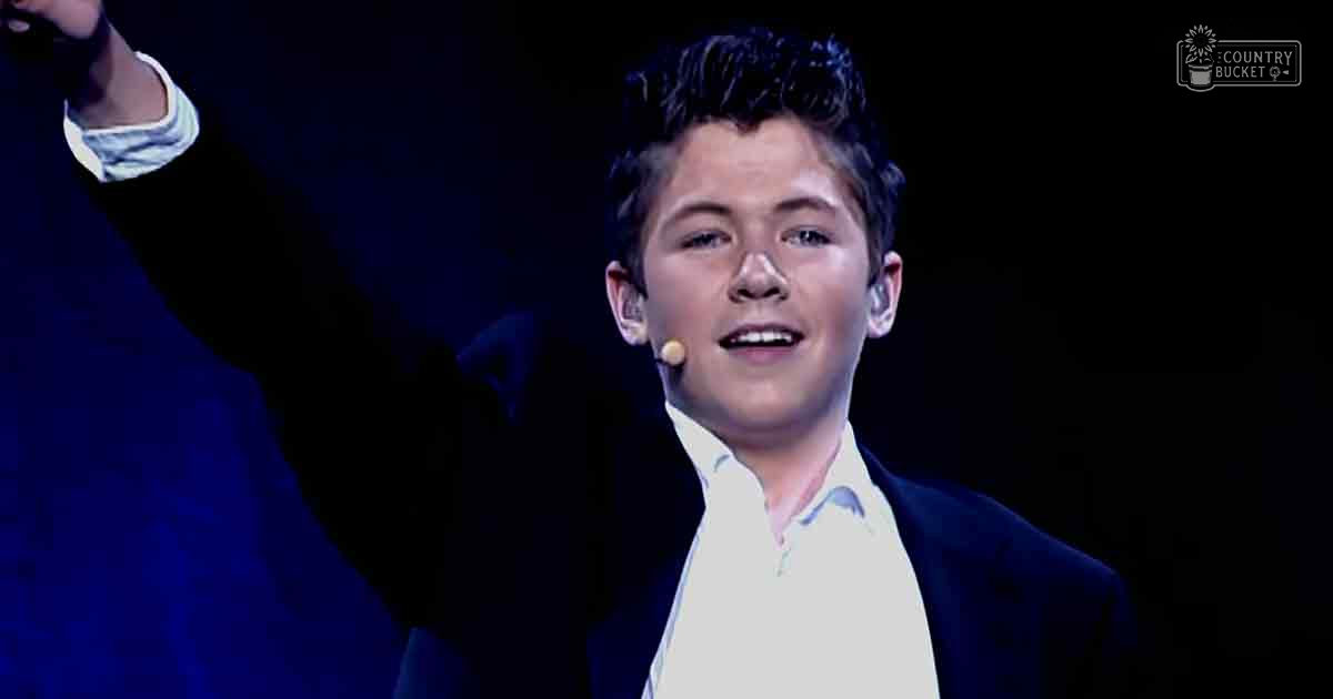Young adult male performer on an indoor stage with dark lighting at night.