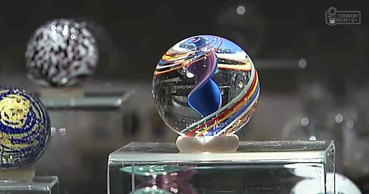 Three intricate glass sculptures on display stands in a dimly lit art gallery setting