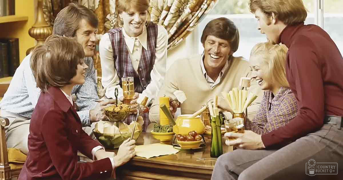 A group of adults gathered around a wooden dining table indoors during daytime with natural light.