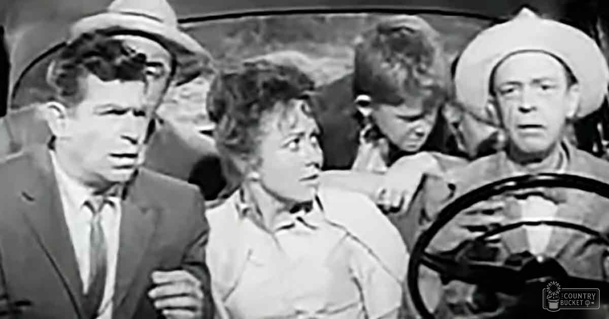 An old Western movie scene set in a desert environment with an adult male driving a car, a middle-aged man on the left, and young adults in the center.
