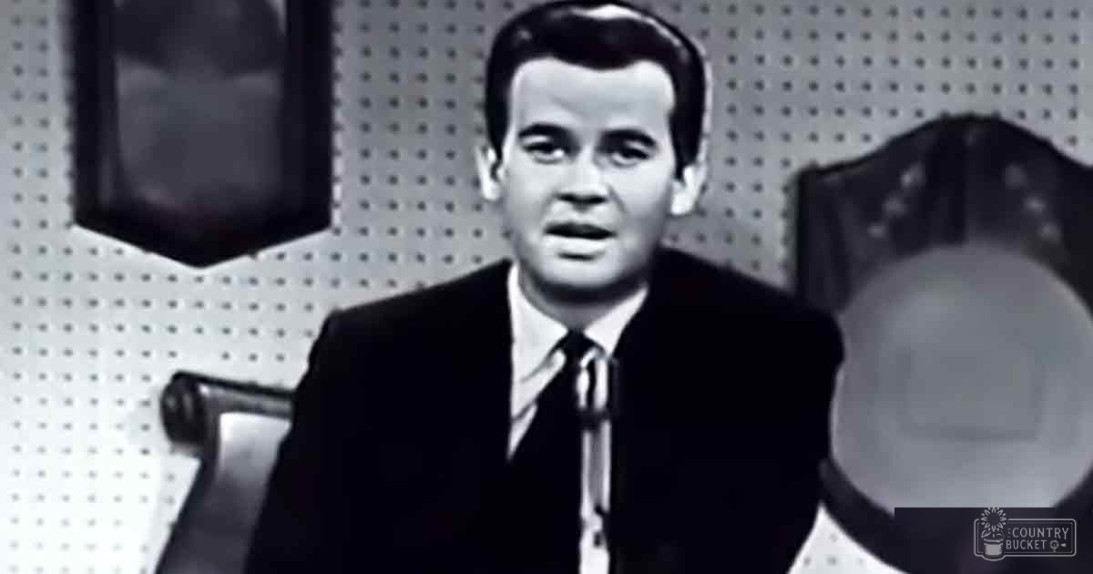 Adult male wearing a dark tailored suit jacket with white shirt indoors.
