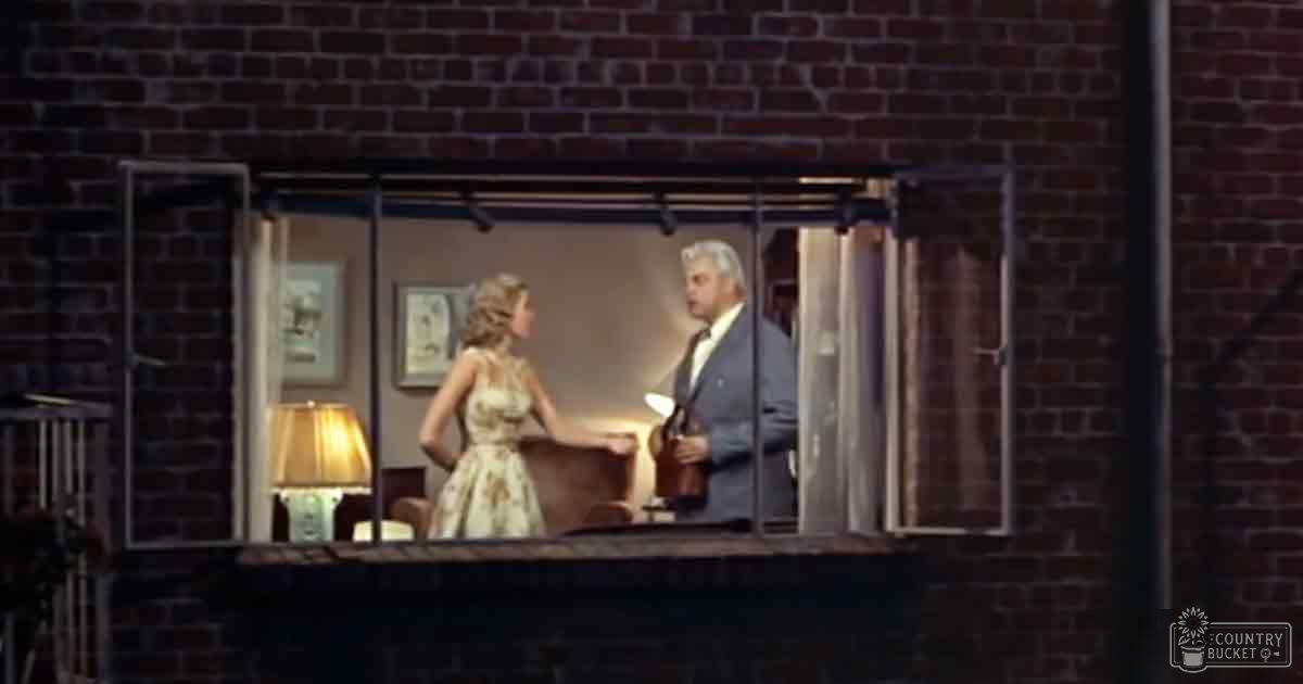 An urban apartment scene at night with brick walls and a window; vintage furniture and framed pictures adorn the space.