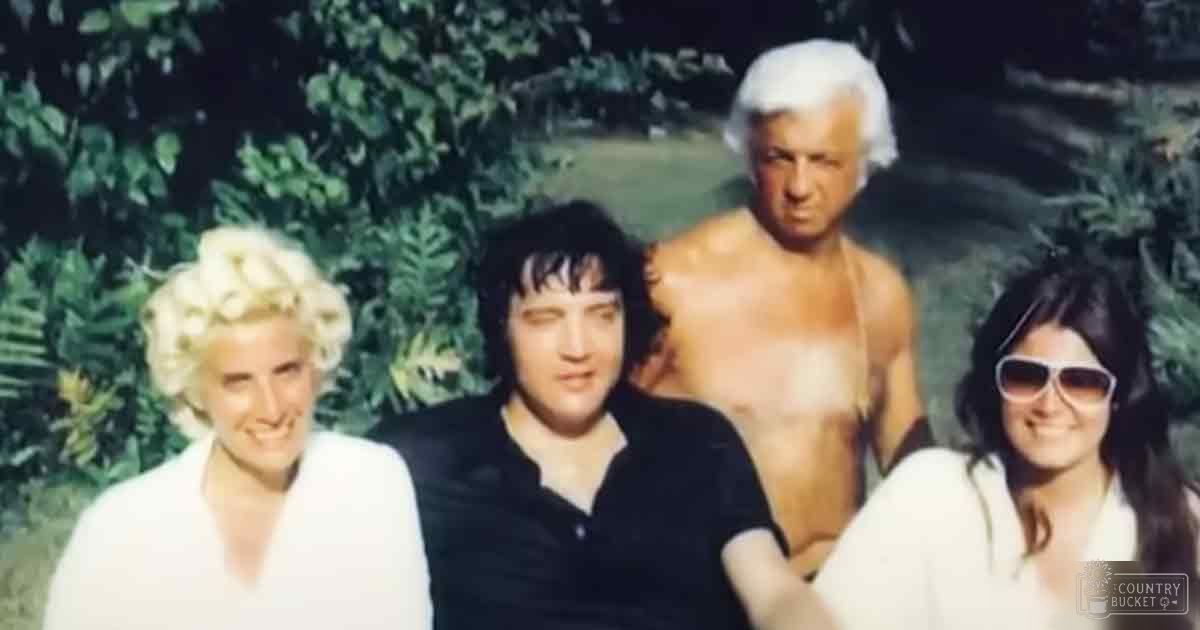 Three adults outdoors near greenery; one in white robe smiling, another in black polo shirt, third in white robe with sunglasses, all standing on grassy terrain with lush foliage behind them.