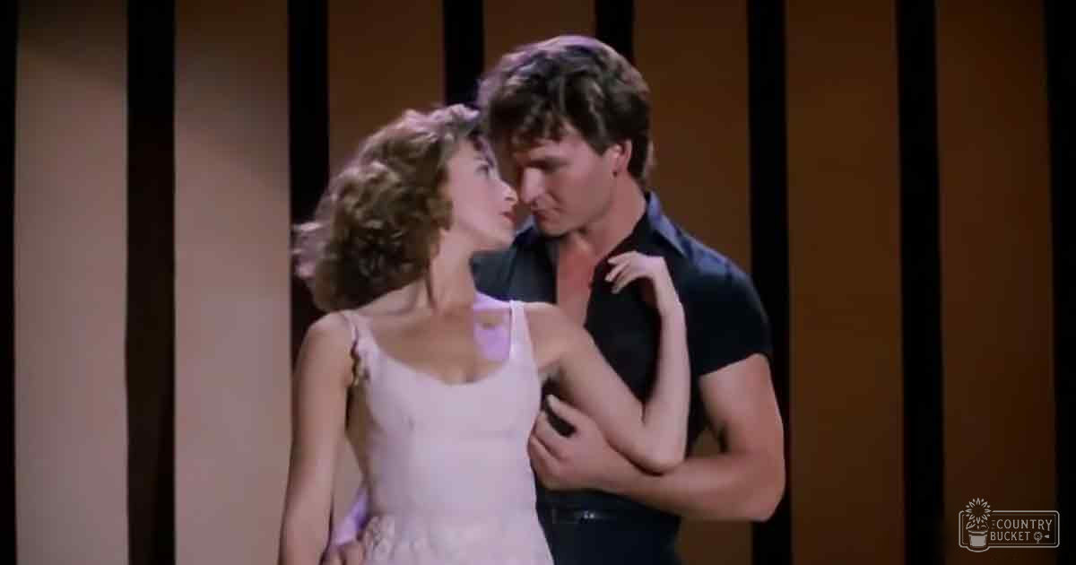 A young adult female wears a light pink sleeveless dress with thin straps, while an equally young male dons a dark short-sleeved shirt and dark pants in an indoor setting.