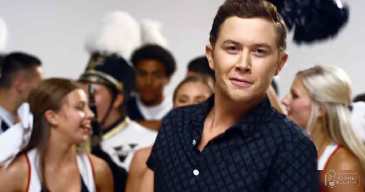 A young adult male and children in cheerleading uniforms are gathered indoors, possibly at a school or community hall event.