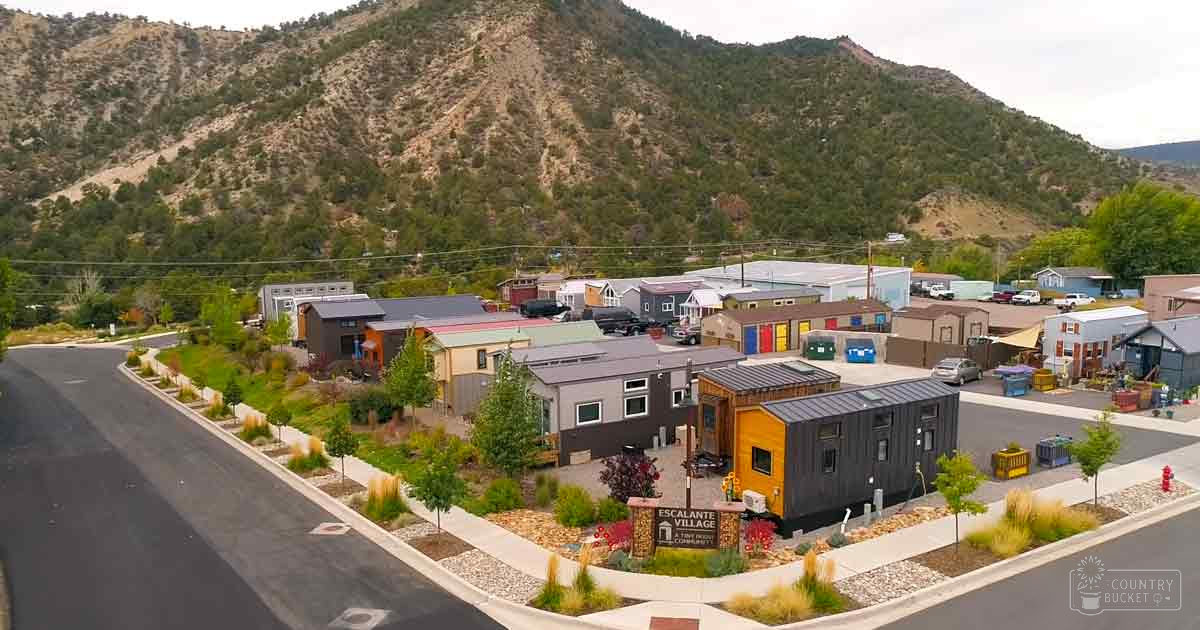Escalante Village, a mountainous residential area with colorful homes and parked cars under overcast skies.