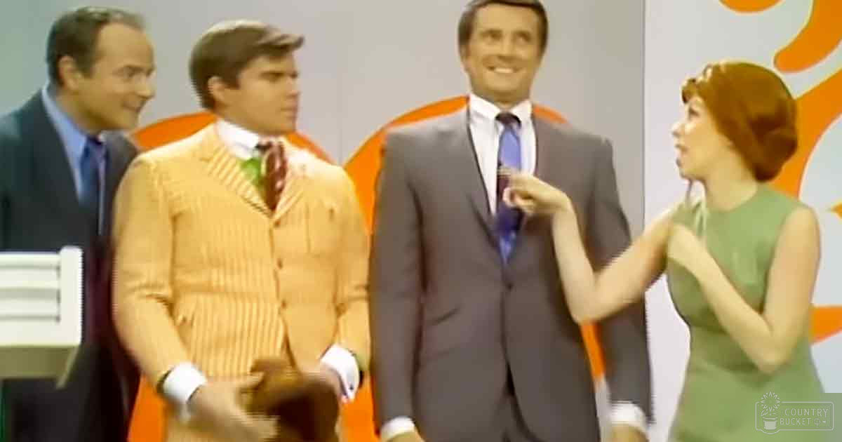 A group of adults dressed formally in a studio setting with an orange and white patterned background.