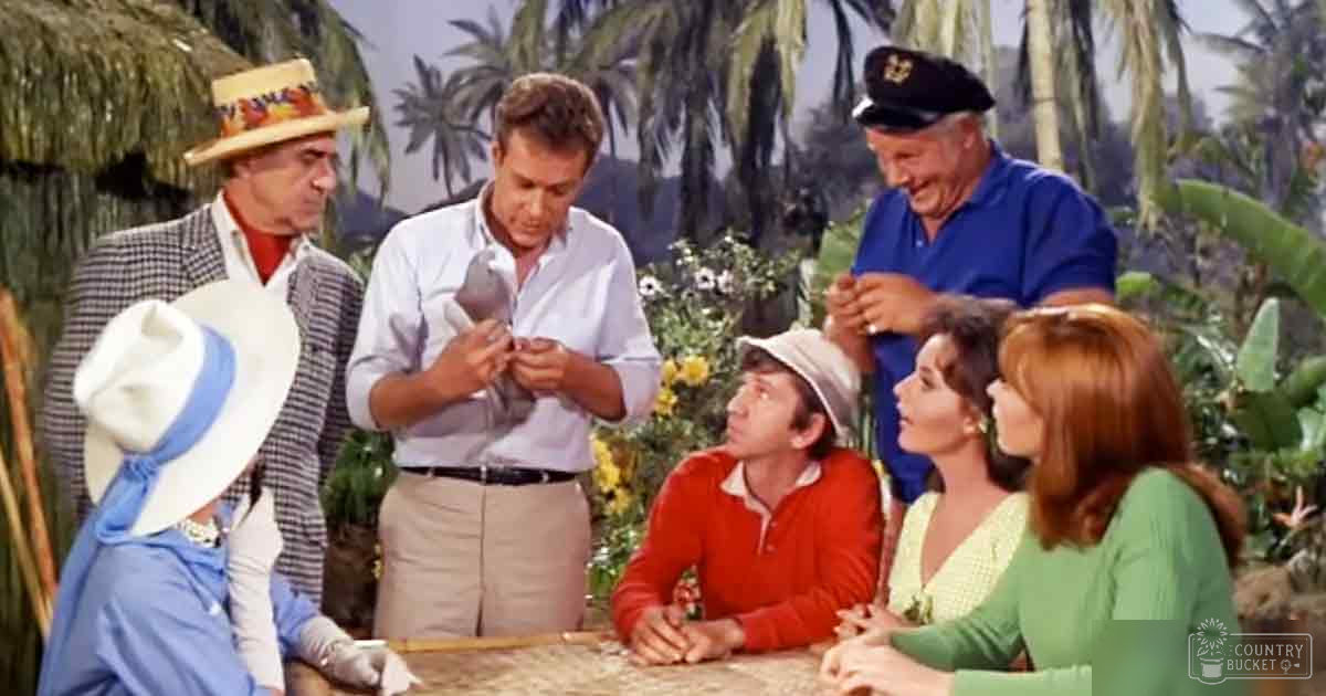 Adult male holding a small animal in front of a group with tropical palm trees in the background, midday scene with clear skies and lush greenery.
