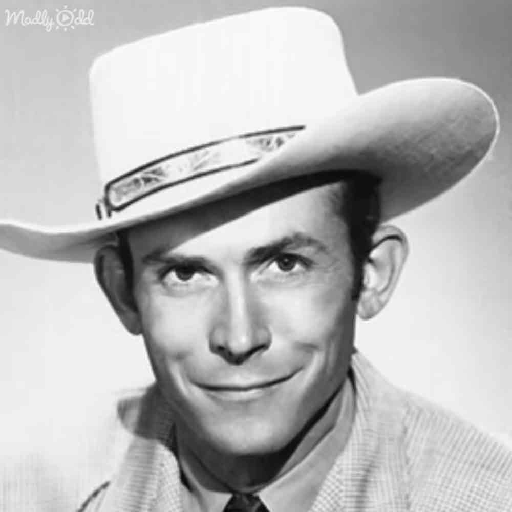 A middle-aged adult male wearing a cowboy hat, checkered shirt with long sleeves, and tie in an indoor setting during daytime.