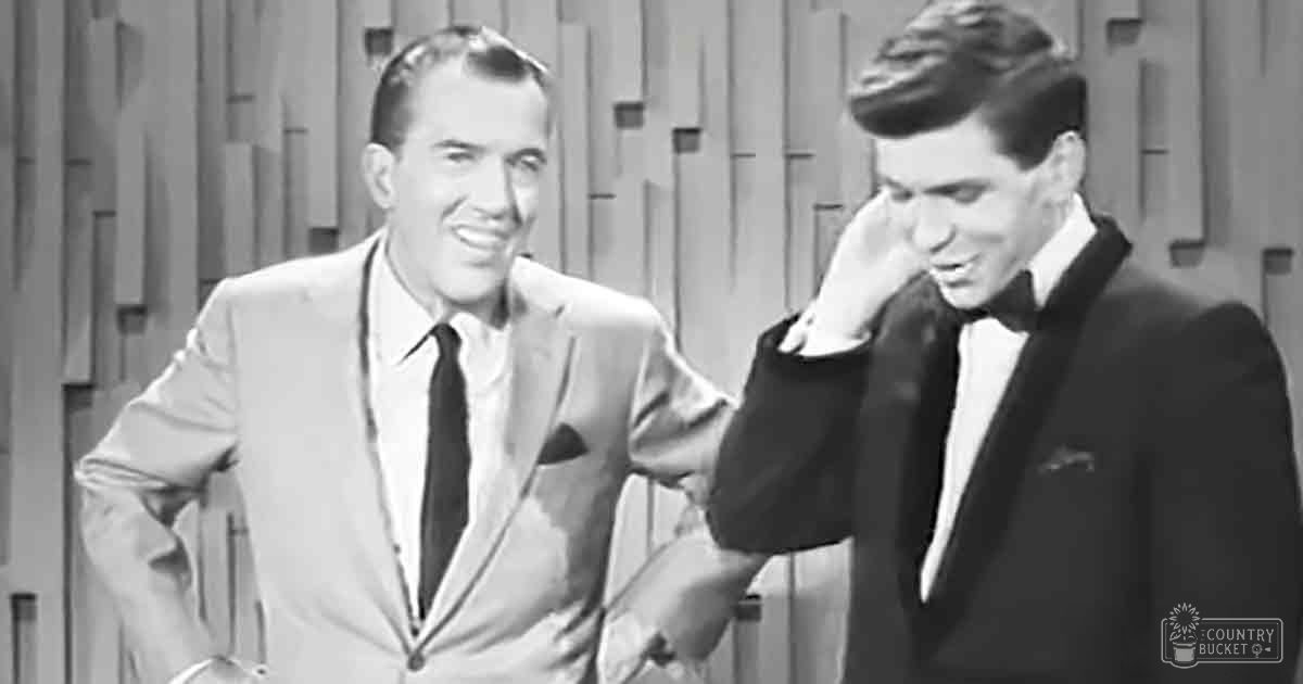 Adult male singer wearing a light-colored suit with dark tie and white shirt; young adult male in a dark tuxedo with white shirt and black bow tie, both set against patterned wall resembling wood paneling in a mid-20th century television studio.