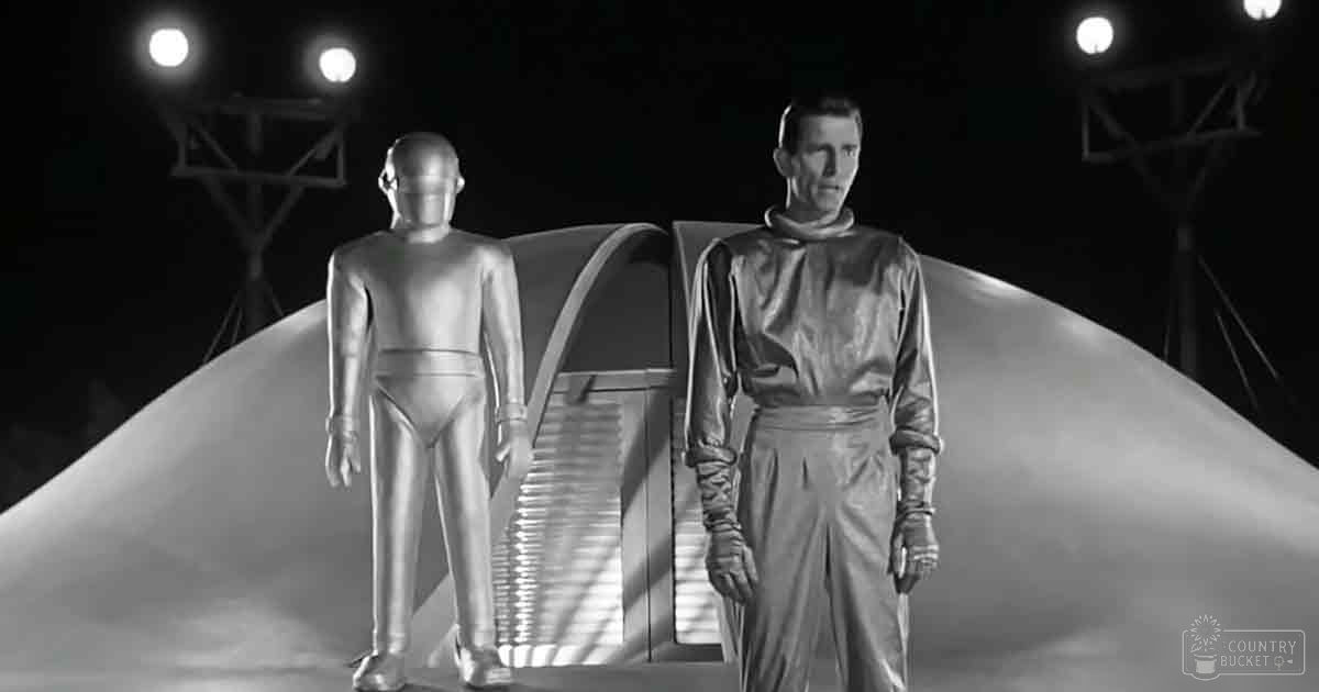 A futuristic indoor scene resembling an alien spaceship or laboratory with two humanoid figures and a staircase in the background.