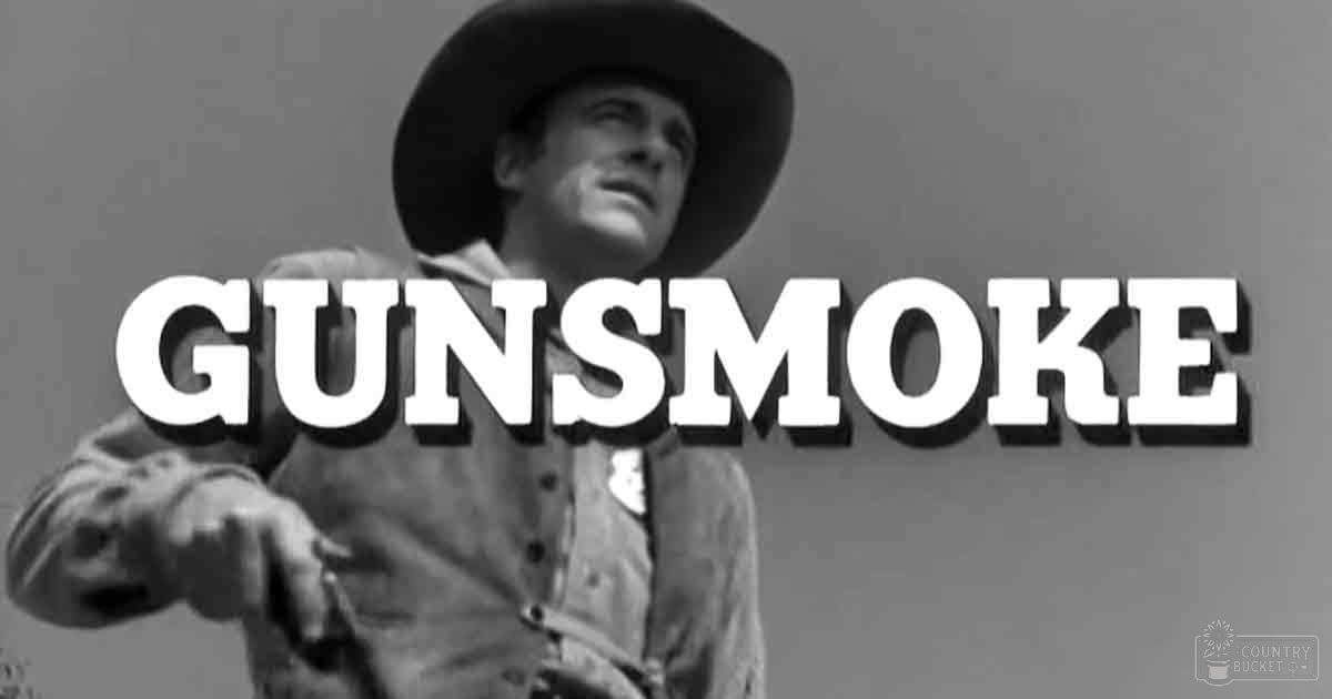 Adult male cowboy in front of 'Gunsmoke' title, wearing wide-brimmed hat and denim shirt, outdoors with a bright daytime setting.