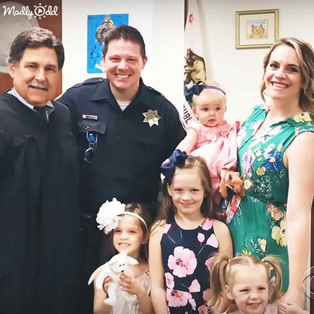 Family photo taken indoors at an official setting, possibly a police station; formal attire and decor suggest an office environment.