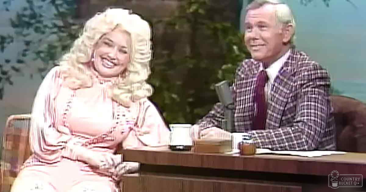 Two adults in a studio setting with an outdoor backdrop; pink dress and plaid blazer stand out.