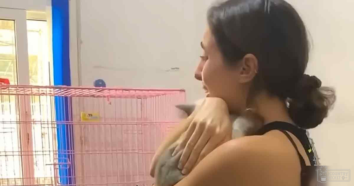 Young adult female in black sleeveless top indoors near pink playpen and white wall.