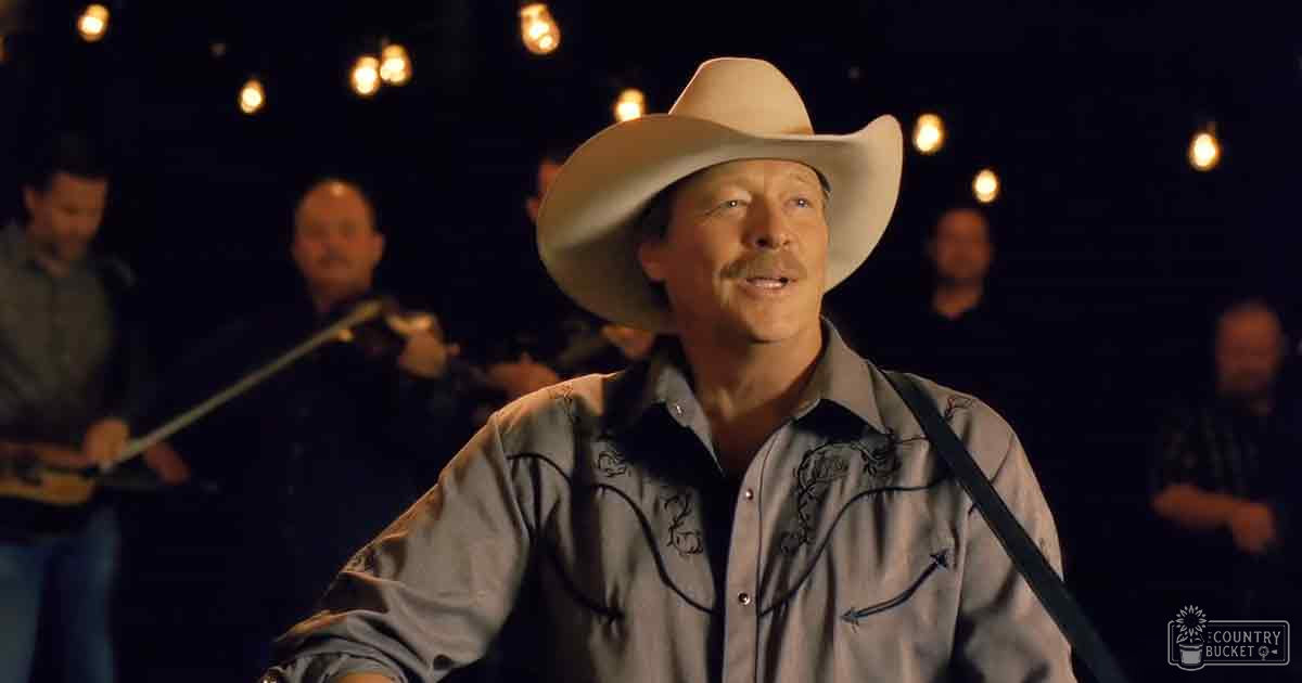 A middle-aged man wearing a light-colored long-sleeve shirt and a wide-brimmed cowboy hat at an outdoor event.