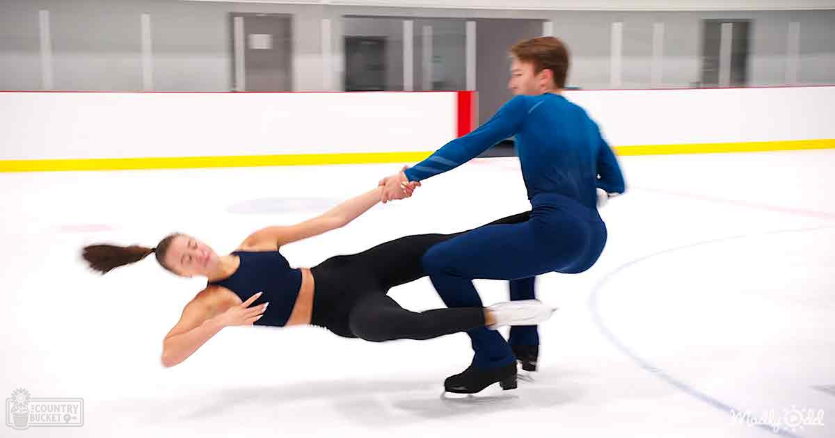 Young adult male and female figure skaters practicing on an indoor ice rink with white flooring and red and yellow boundary lines under artificial lighting.