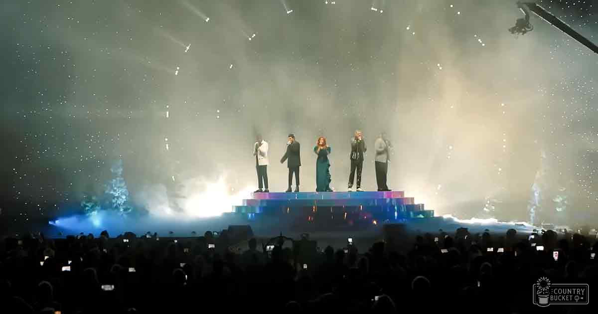 A concert scene at an indoor venue with a starry sky effect above; audience in silhouette holding up phones or cameras to capture the performance.
