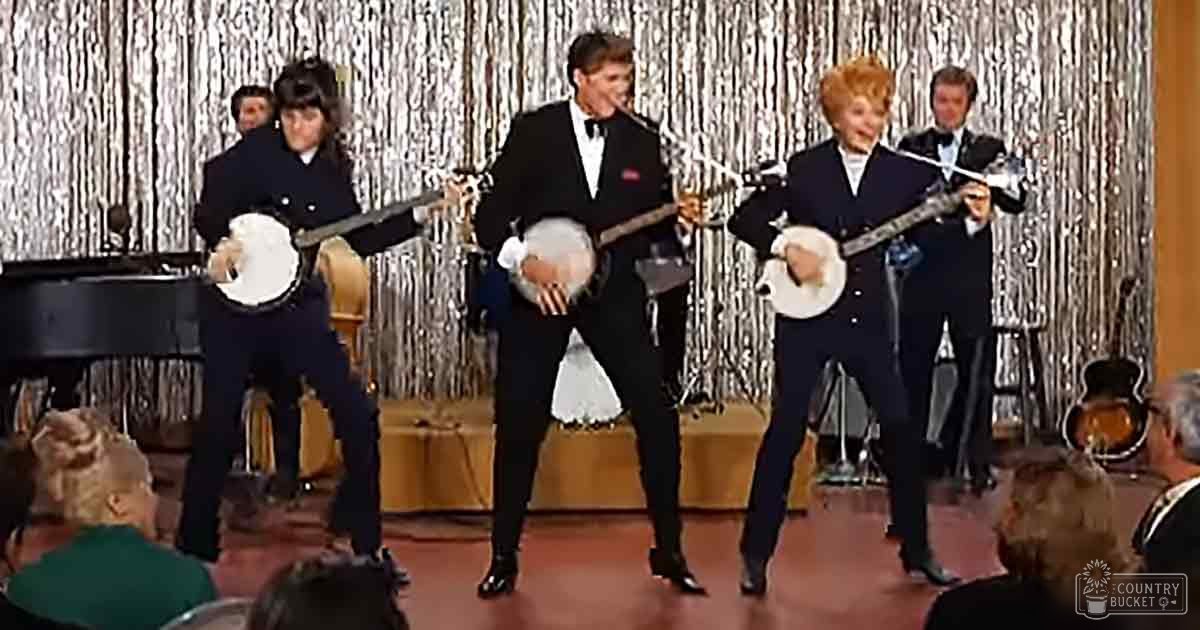 Musical performance with banjo players indoors with festive silver tinsel curtains and dark red stage floor.