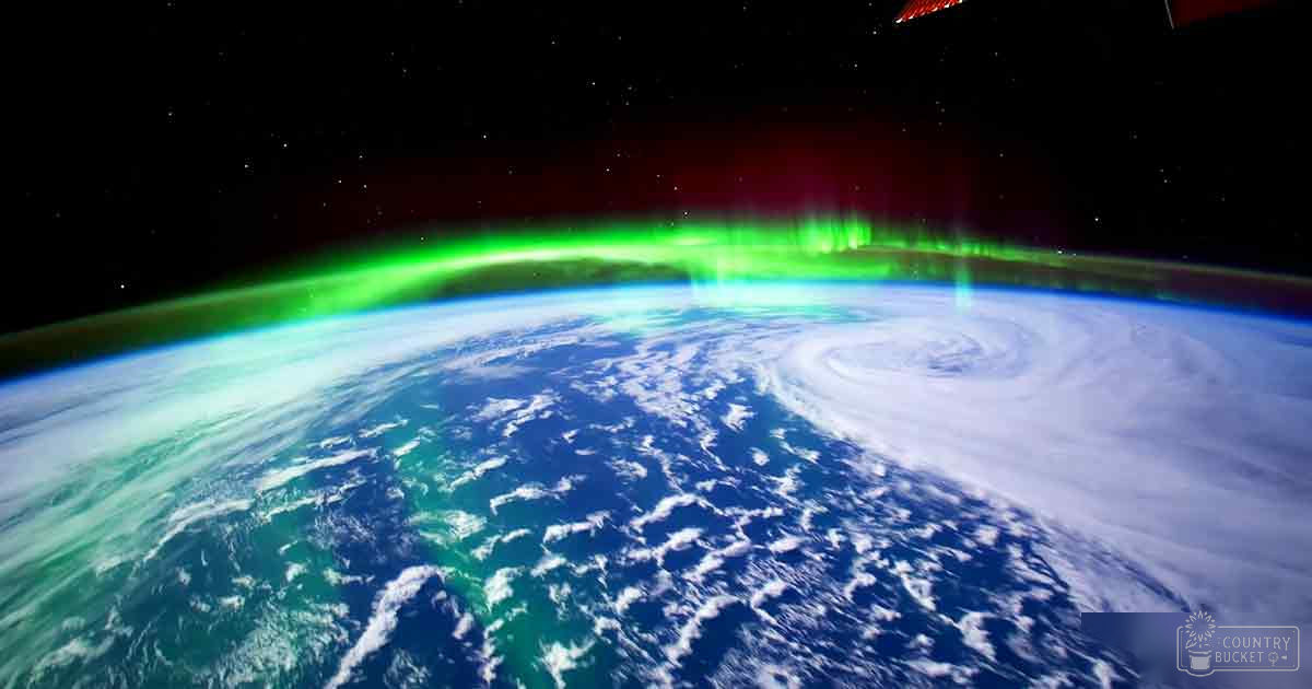 Earth from space with visible auroras at night showing clouds, oceans, landmasses against a starry background