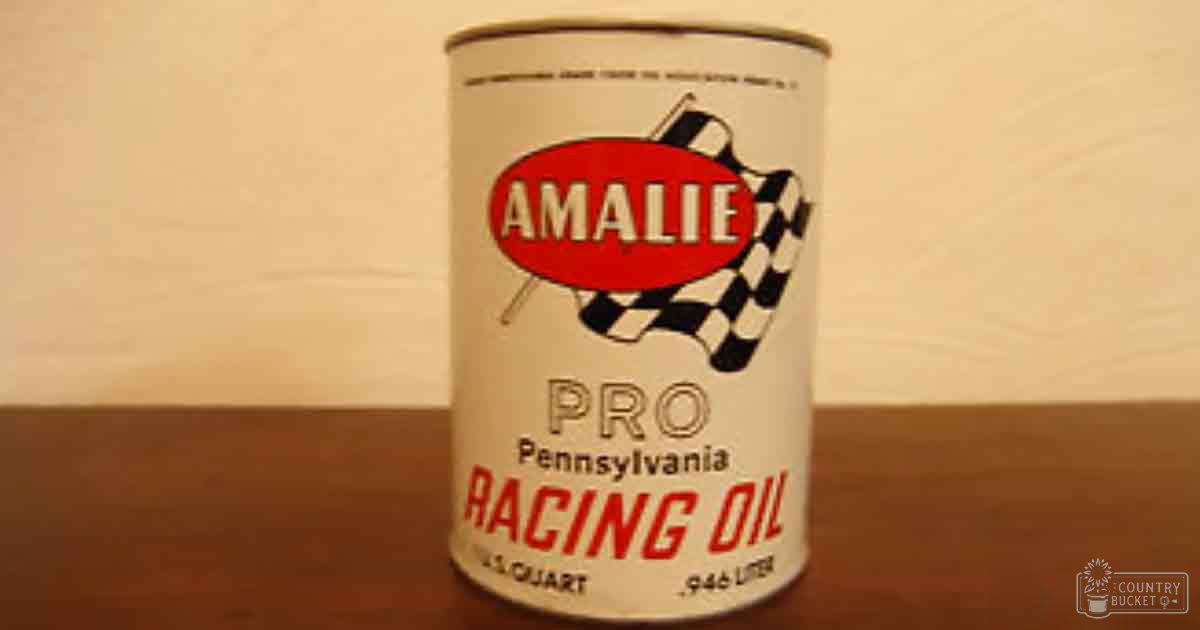 Close-up of a vintage Amalie Pro Pennsylvania Racing Oil can with a checkered flag pattern on a wooden surface indoors.