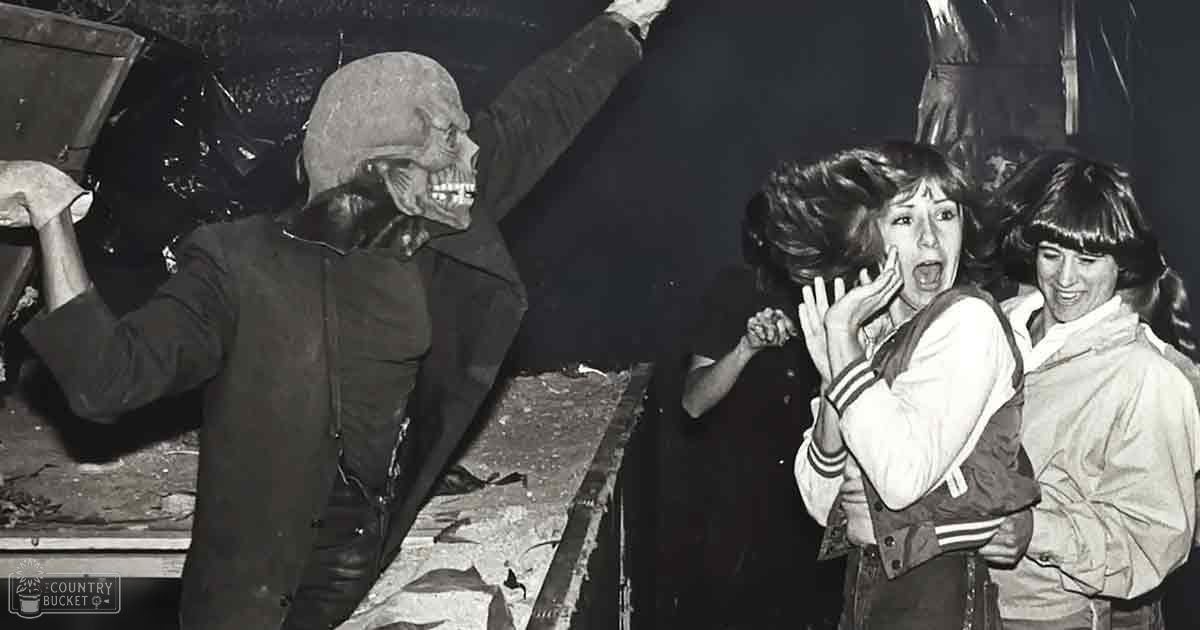 An outdoor Halloween event at night with people dressed in costumes and casual attire, illuminated by artificial lighting.