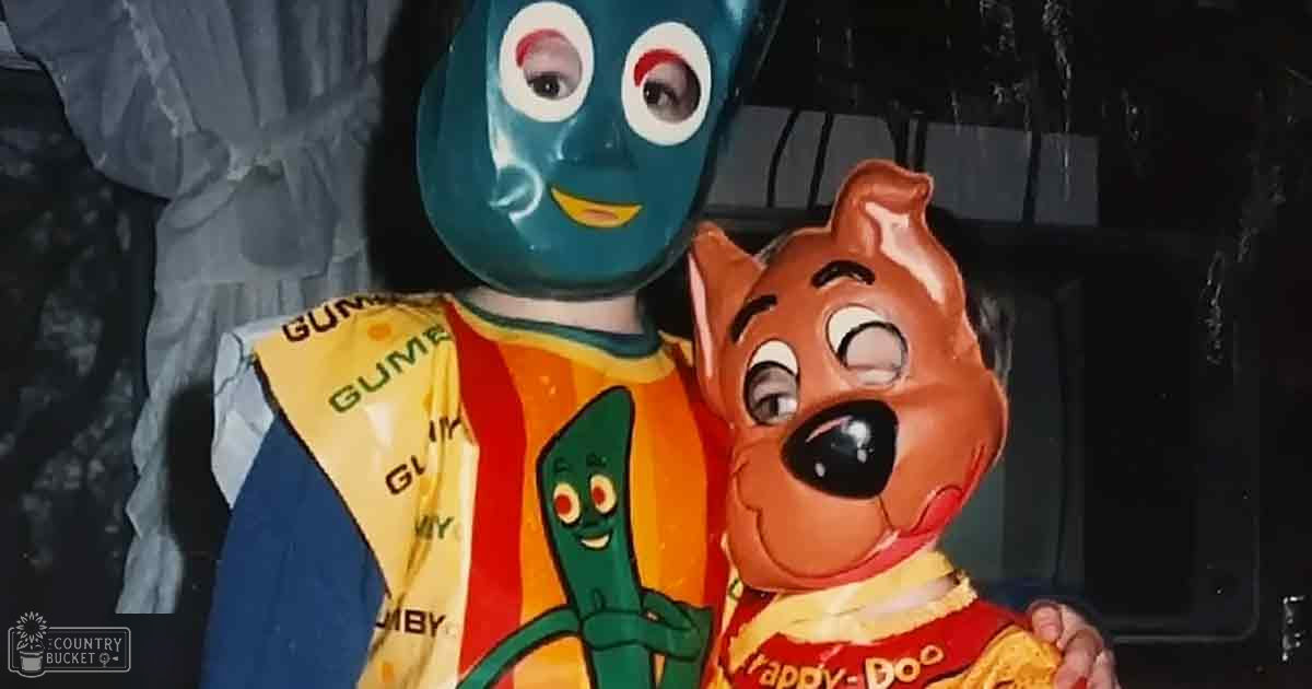 Two individuals dressed as Gumby and Scooby-Doo characters, wearing masks and themed shirts in an indoor event setting with dark walls.