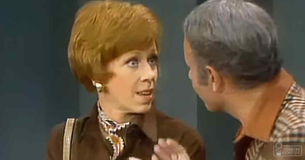 Two adults in an indoor setting, one woman wearing a patterned top and earrings, holding a microphone, another man with short-sleeved shirt.