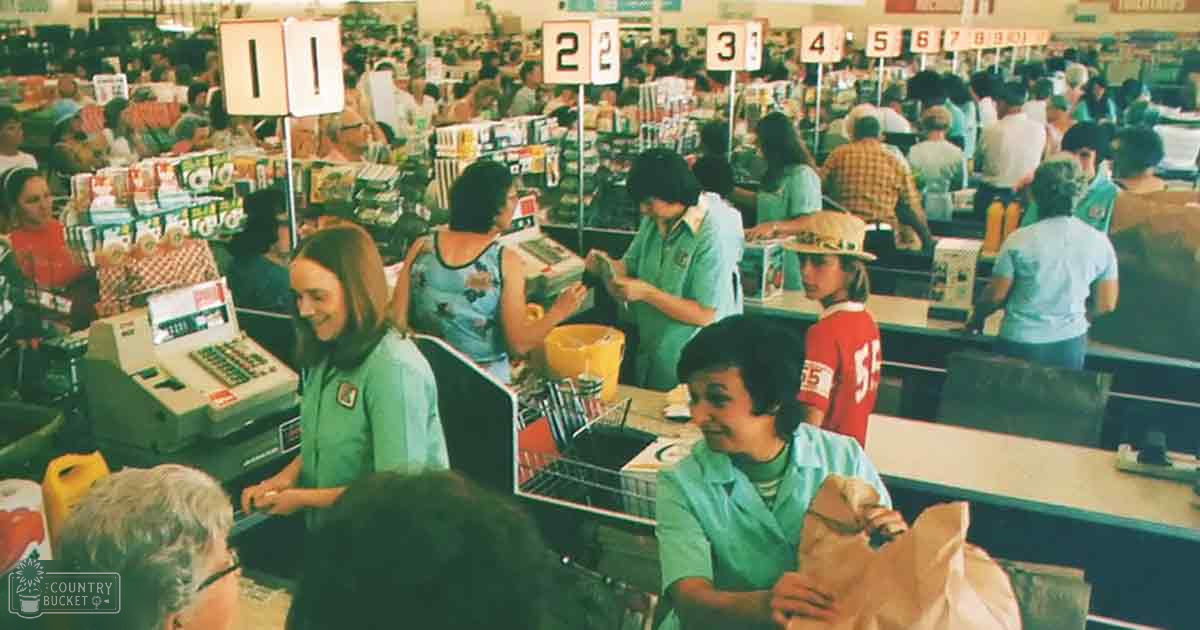 A busy checkout area in an old-fashioned supermarket with people wearing mid-century uniforms and casual attire.