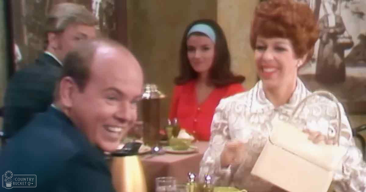 Adult male and two women seated at an indoor dining table with vintage decor, natural light suggests daytime setting.