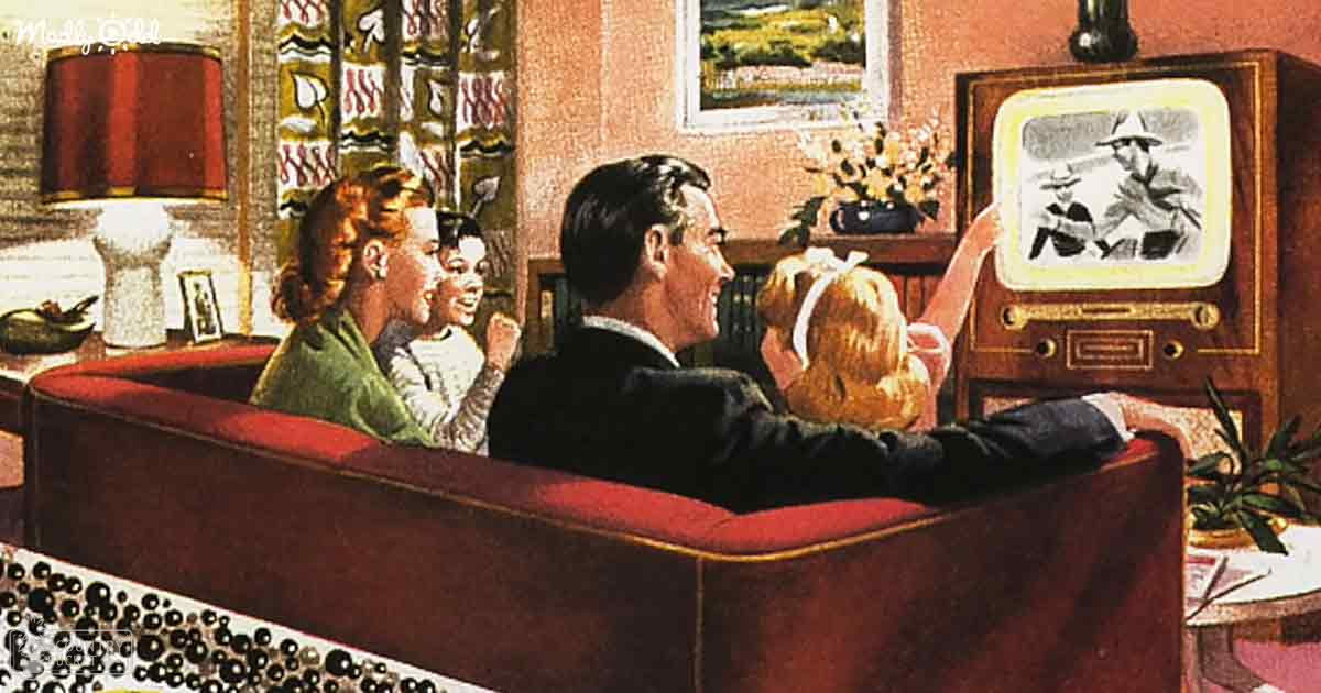 A family of four watching television in their living room, with a red upholstered sofa and vintage-style wooden television cabinet with knobs.