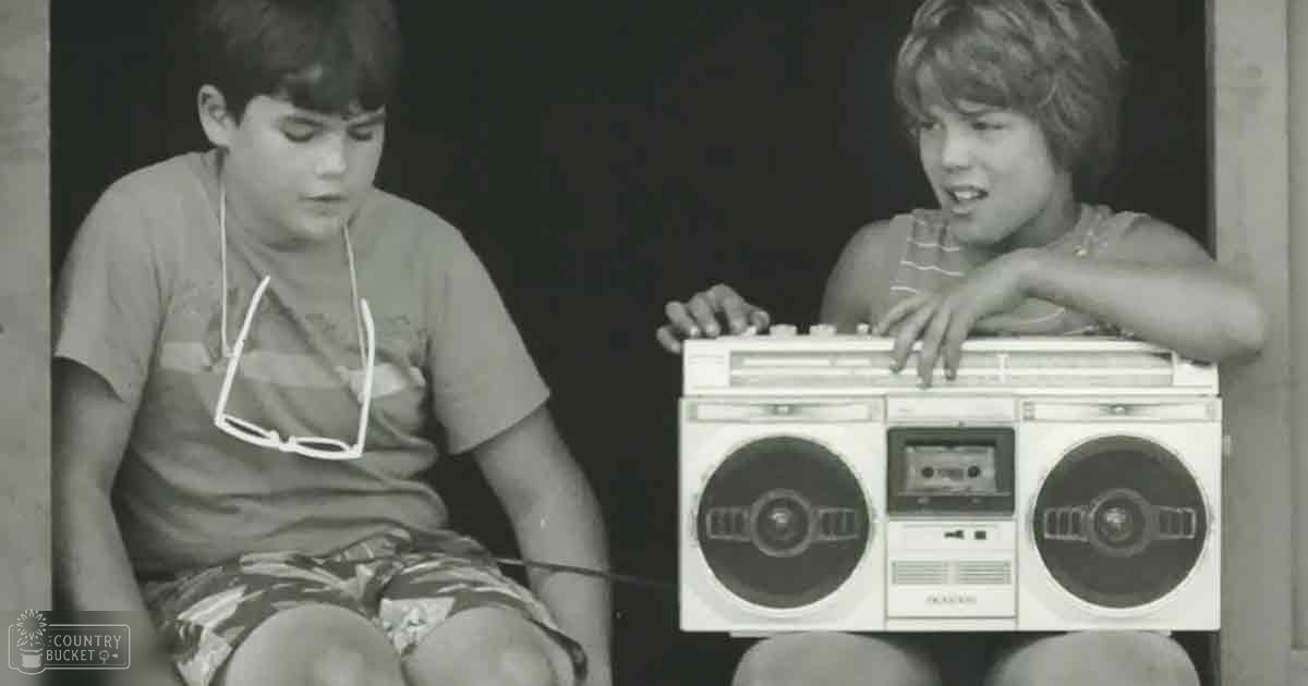 Two children in a casual indoor setting with a boombox as the central object.